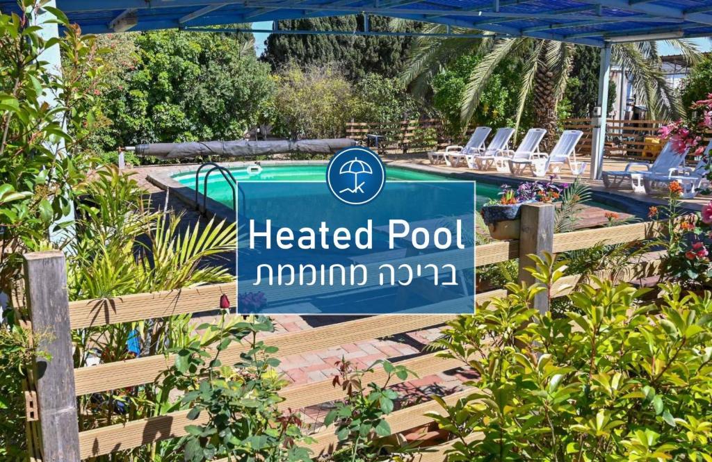a sign for a heated pool in a garden at YalaRent Valley view complex In Merhavia with Private Pool in Merhavyāh