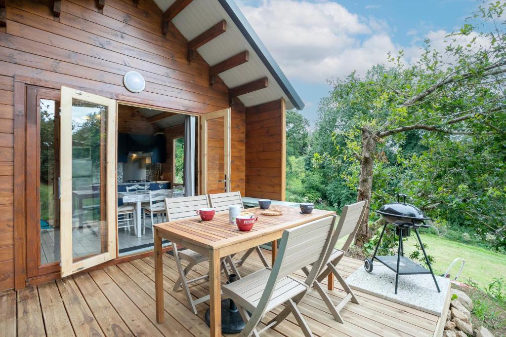 a wooden table and chairs on a deck with a grill at Ty Koad in Plouégat-Moysan