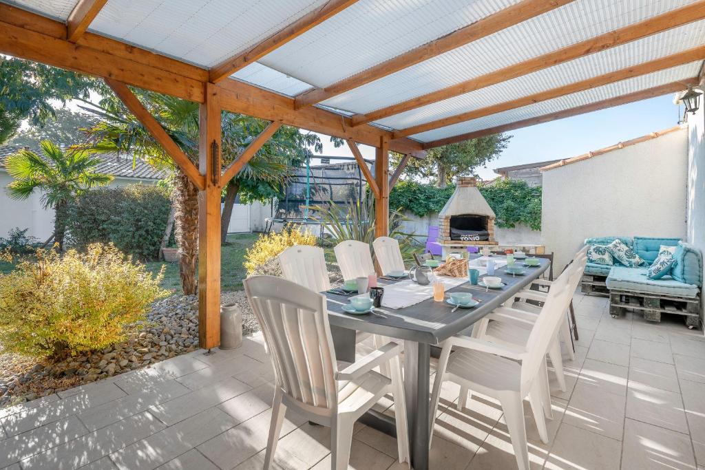 einen Tisch und Stühle auf einer Terrasse mit einer Pergola in der Unterkunft Jacuzzi Maison pour 11 au calme plage a 500m in Le Cormier