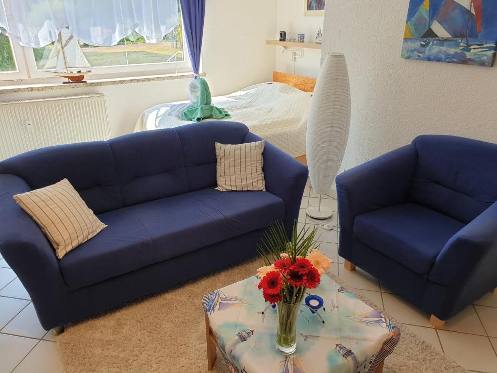 a living room with two blue couches and a table at Ferienwohnung Strandperle-Schilksee in Kiel