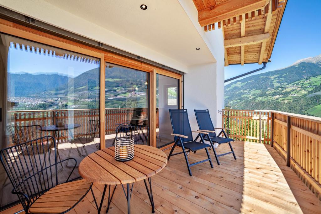 a balcony with a table and chairs and mountains at Huetterhof Apartement Langes in Caines