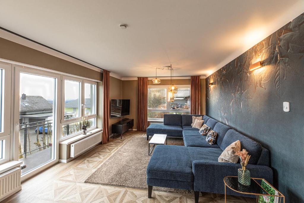 a living room with blue couches and a large window at Haus Cervus in Hattgenstein