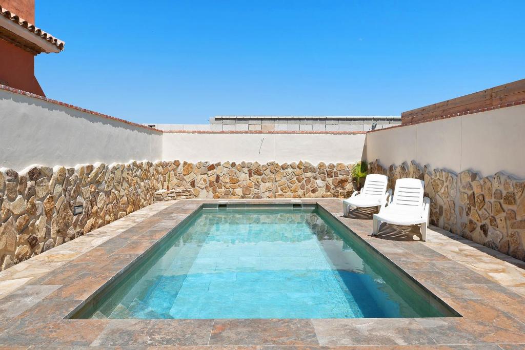 a swimming pool with two chairs next to a wall at Casa Juana Zahora in Zahora