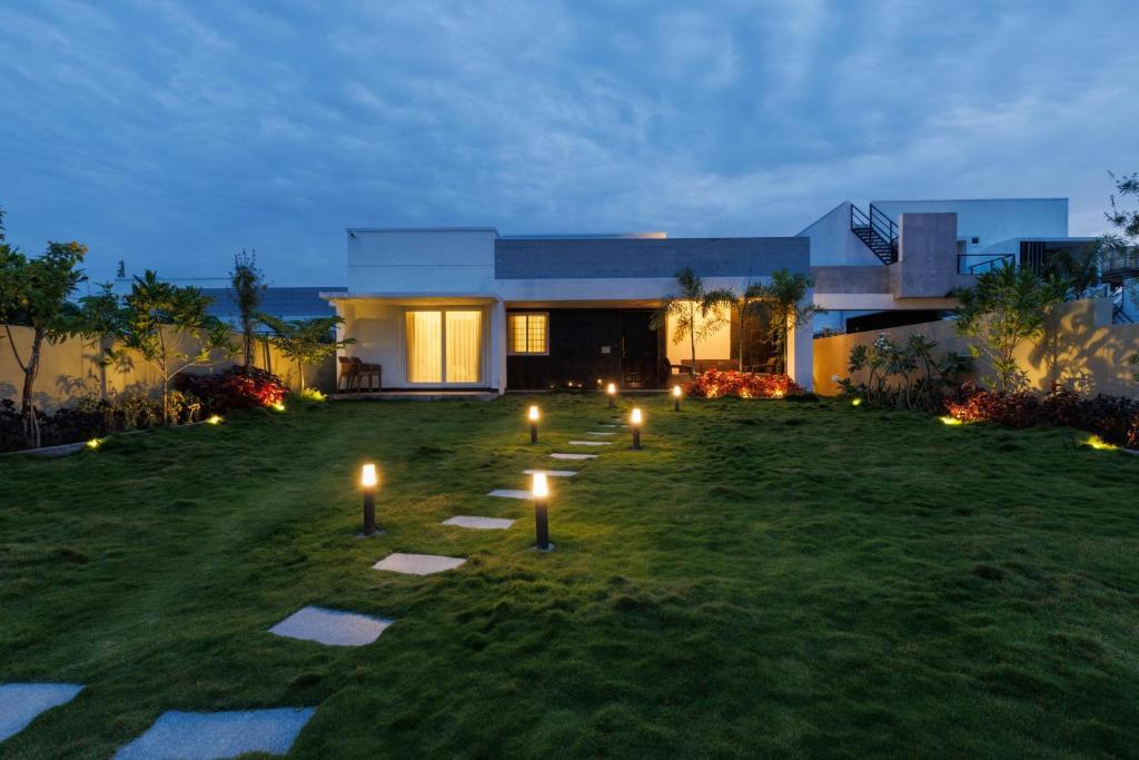 a house with candles in the yard at night at The Garden Retreat by StayJadePool2BHKLawn in Berikai