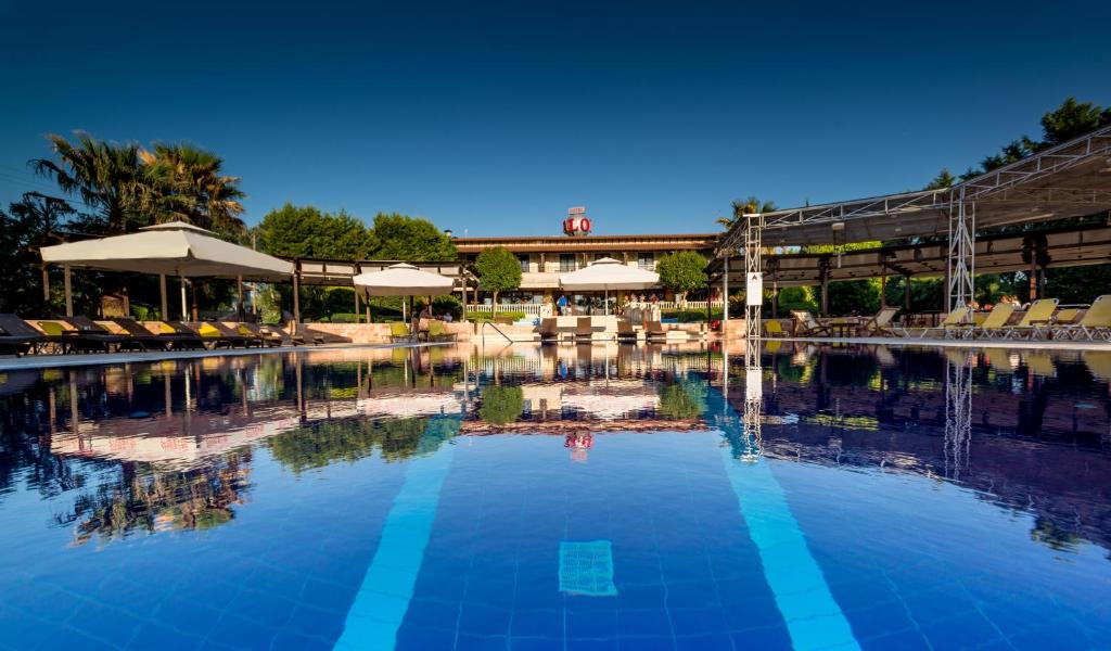 a pool at a resort with chairs and umbrellas at Avalon Airport Hotel Thessaloniki in Thermi