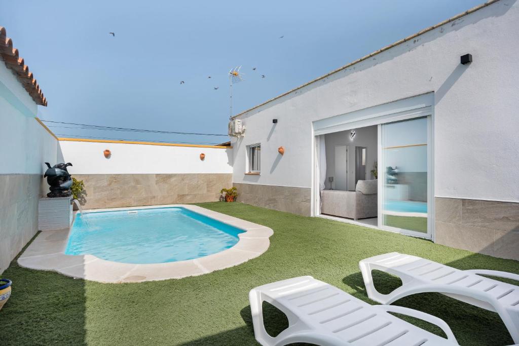 a backyard with a swimming pool and two lawn chairs at La Brujita in Chiclana de la Frontera