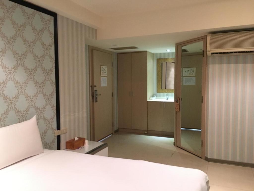 a bedroom with a white bed and a kitchen at Daylight Hotel in Zhonghe