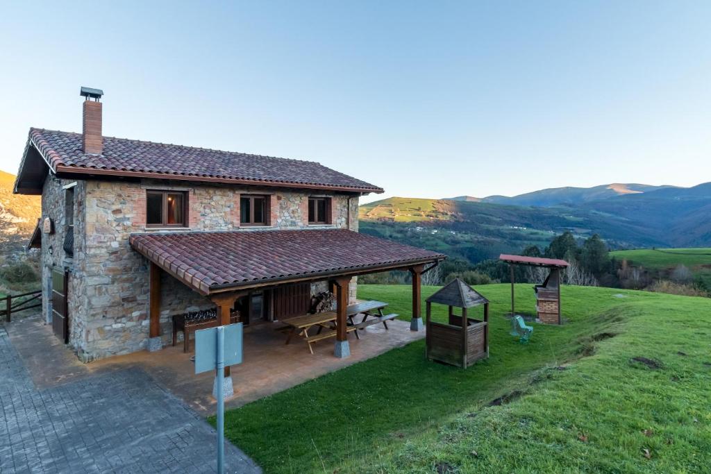 a small stone house with a picnic table and a grill at El Paraiso del Yayo in Ramales de la Victoria