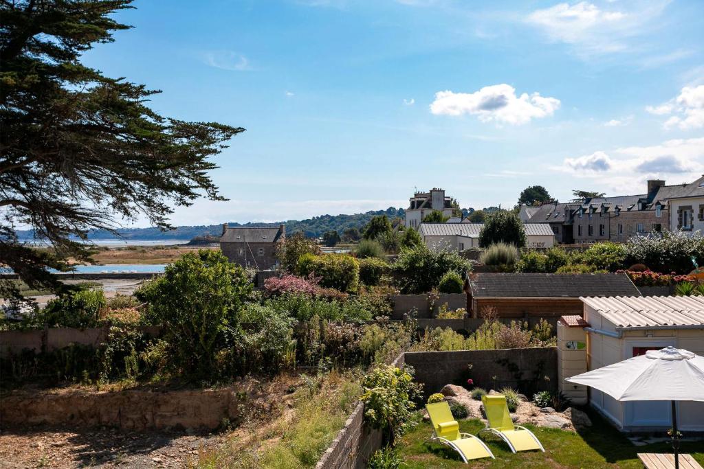 a view of a garden with yellow chairs and buildings at Le paradis sur mer in Paimpol