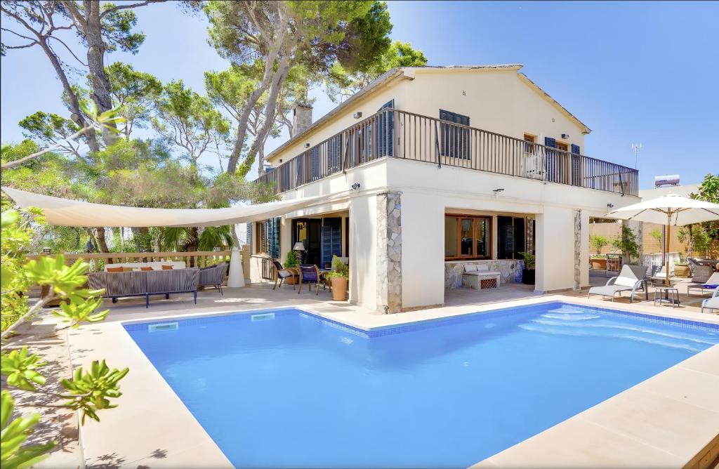 una villa con piscina frente a una casa en Villa Cala Estancia Mercedes, en Can Pastilla