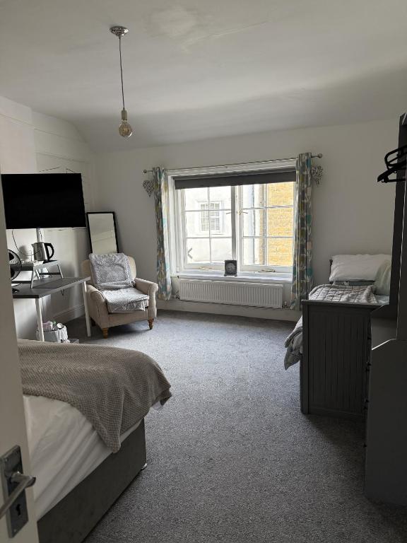 a bedroom with a bed and a window and a chair at The Britannia Inn in Sherborne
