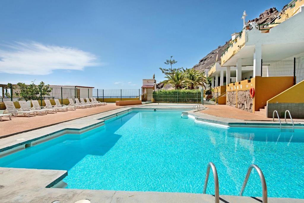 ein Swimmingpool mit Stühlen und das Meer im Hintergrund in der Unterkunft Suite On the Beach in Playa del Cura