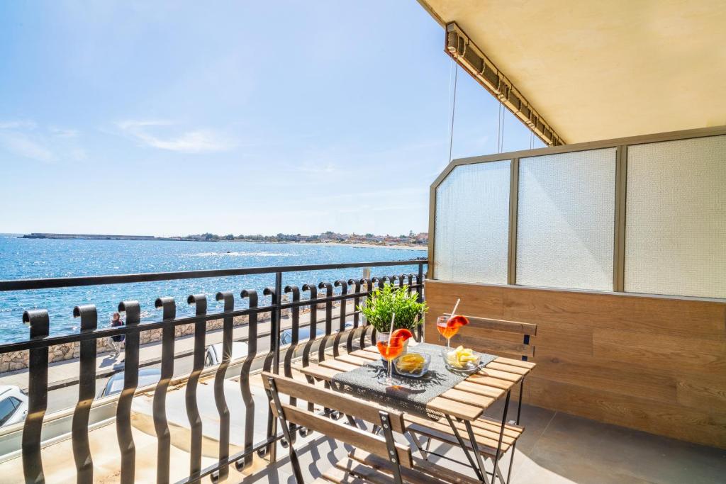 a table on a balcony with a view of the water at Il Fronte Mare di Naxos Luxury Home in Giardini Naxos