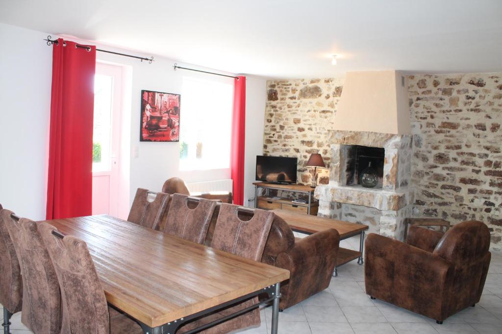 a living room with a table and chairs and a fireplace at Les Ecuries in Saint-Maurice-en-Cotentin