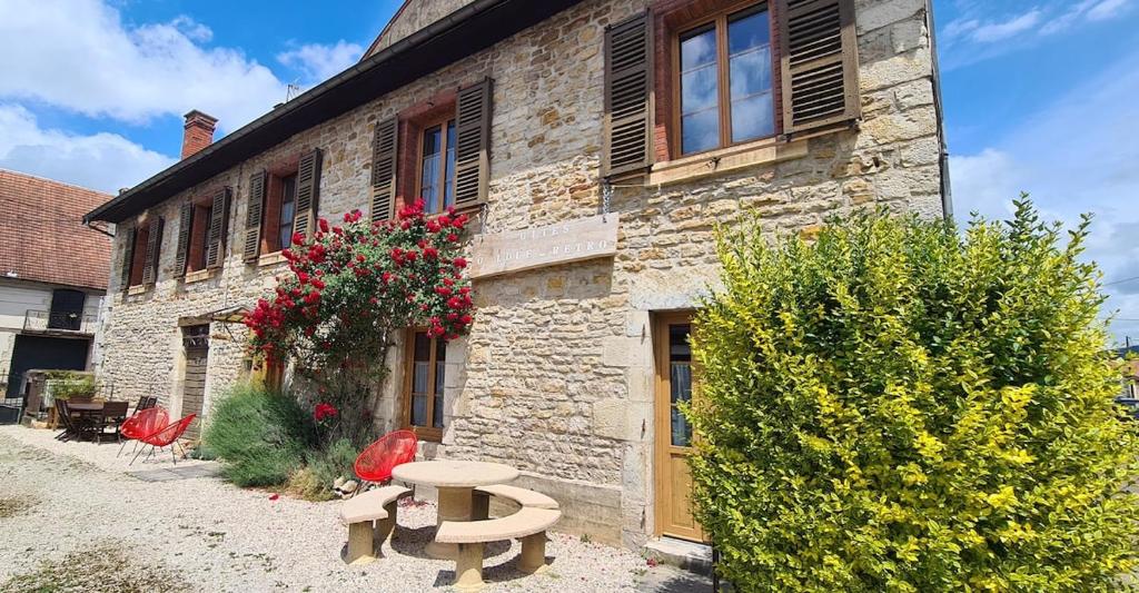 ein Steingebäude mit zwei Bänken davor in der Unterkunft Ô Loue Rétro - 6 personne - 1er étage in Quingey