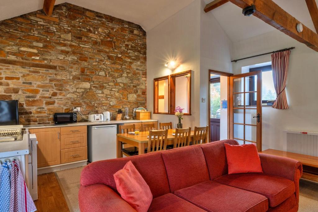 ein Wohnzimmer mit einem roten Sofa und einer Küche in der Unterkunft Finest Retreats - Warren Cottage, Stowford in Little Torrington