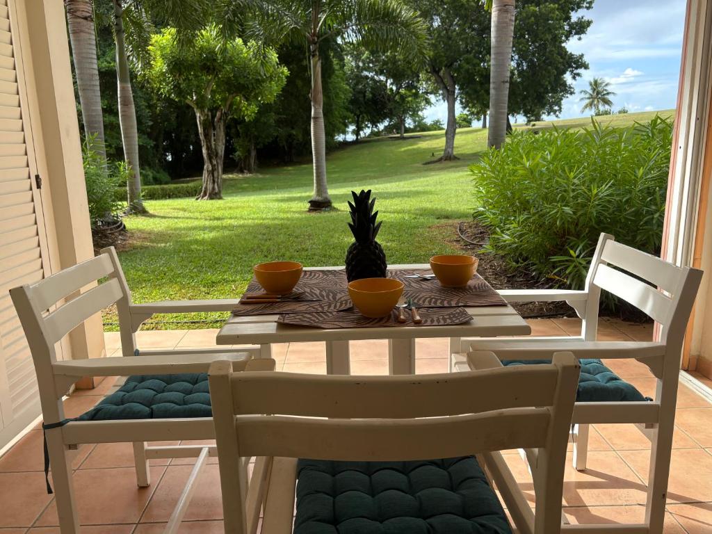 a table with two chairs and a table with a pineapple on it at TI COCOTIER Studio PREMIUM Village Vacances in Sainte-Luce