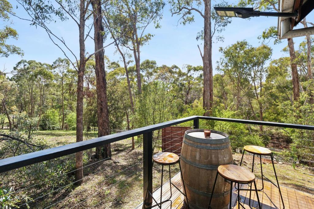 a deck with a barrel and stools on a balcony at Hepbirds in Hepburn Springs