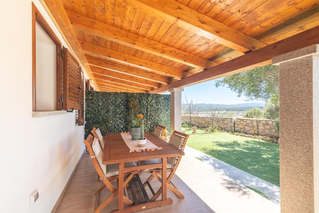 a patio with a wooden pergola and a wooden table at Trilo Nina in Santa Teresa Gallura