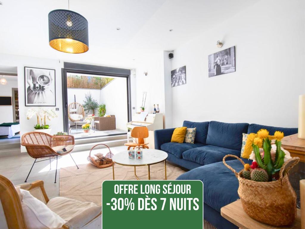 a living room with a blue couch and a table at Loft Saint-Hubert - Idéal Familles & Groupes - 10min Avignon et Château-neuf-du-Pape - 5min Gare - Expérience design, conviviale et tout confort - Jardin clos - Parking privé gratuit - Au calme in Sorgues