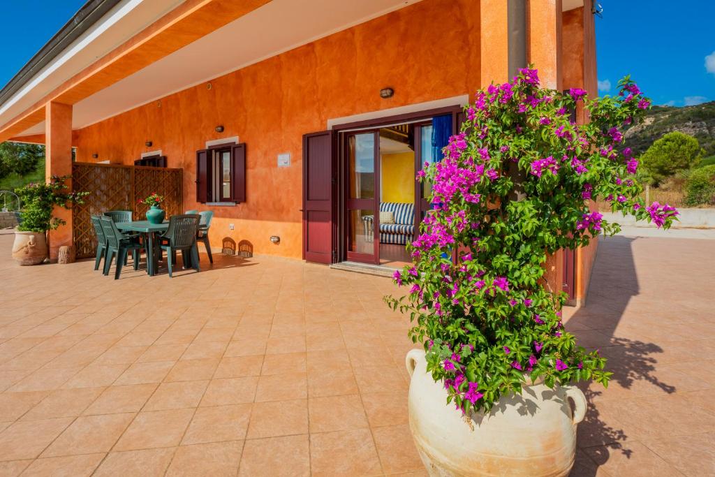 a patio with a table and flowers in a pot at Gli Ulivi Palau - La Zirichelta in Palau