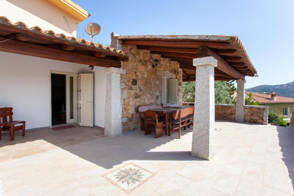 a patio with a table and a stone wall at Appartamento immerso nel verde in San Teodoro