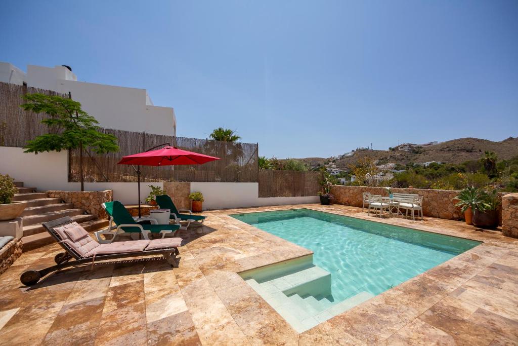 a swimming pool with two chairs and an umbrella at Casa Azahar playa Cabo De Gata 2 in Las Hortichuelas Bajas