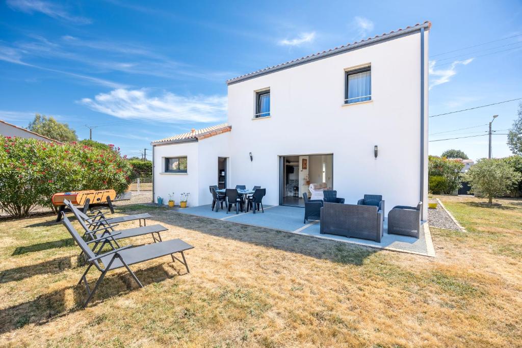 a white house with chairs and tables in the yard at La Maison du Payré - proche plages in Talmont-Saint-Hilaire