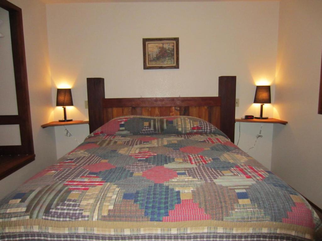 - une chambre avec un lit et deux lampes murales dans l'établissement Almost Paradise Lodging, à Ashford