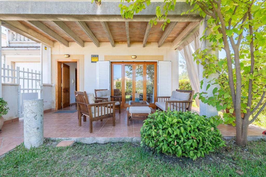a patio with two chairs and a table and some trees at Que Bo in Alcudia