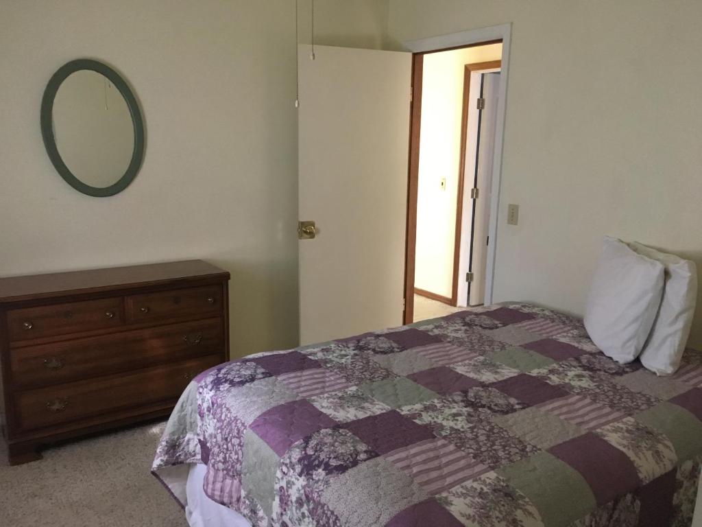 Un dormitorio con una cama, una cómoda y un espejo. en Firefly Beach, en Huron