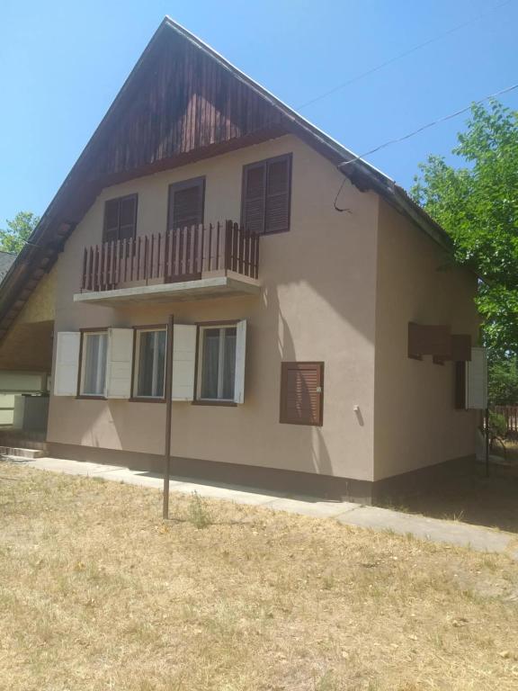 a house with a balcony on the side of it at Tomi Vendégház in Kóczántanya