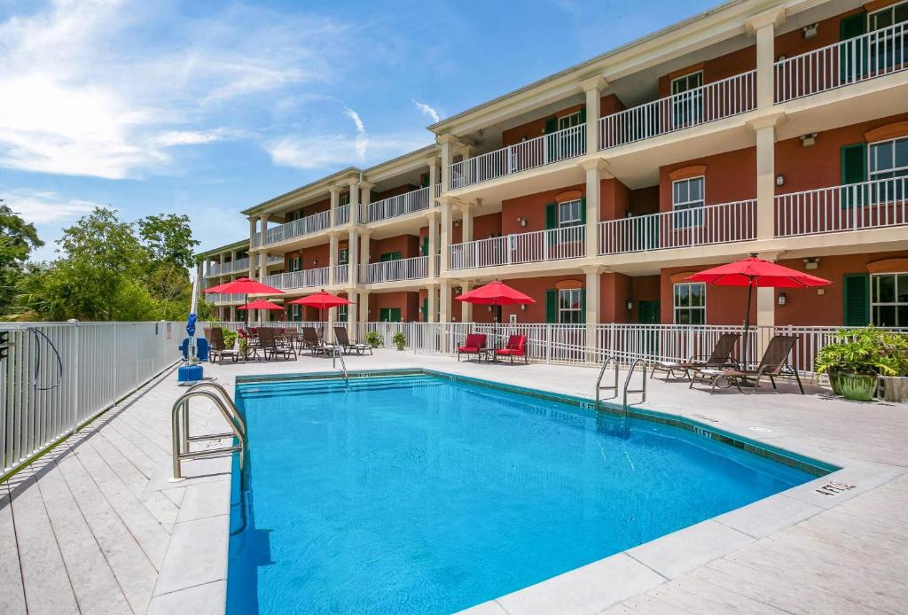 a pool in front of a hotel with red umbrellas at Water Street Hotel & Marina, an Ascend Collection Hotel in Apalachicola