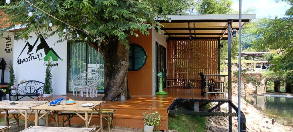 una casa con una mesa y un árbol en una cubierta en Lhong Luk Khao Camping, en Ban Khlong Kathon