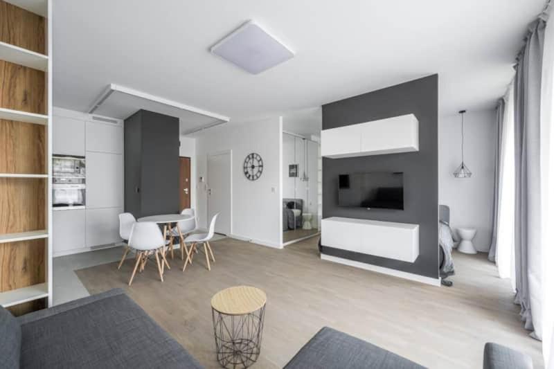 Una sala de estar con una mesa y sillas y un televisor. en Exclusive Apartments on Kasprzaka Street - Warsaw Wola, en Varsovia