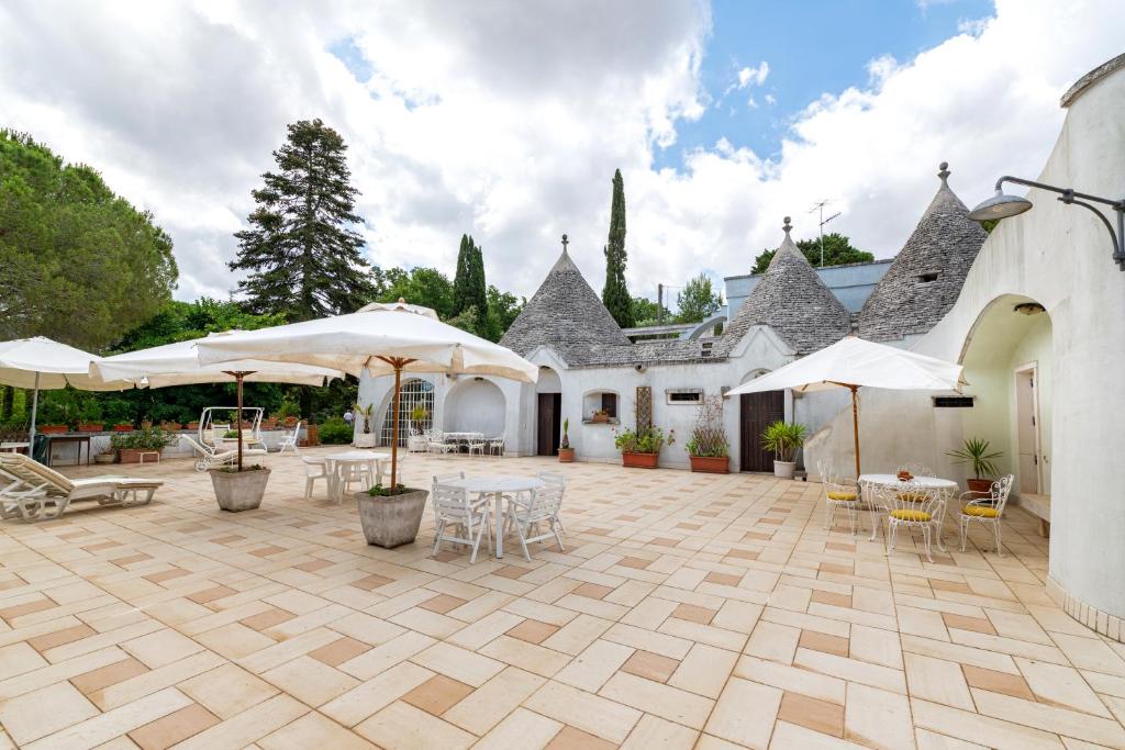 Un patio con mesas, sillas y sombrillas. en Casa delle Zagare, Borgo del Mirto, en Selva di Fasano