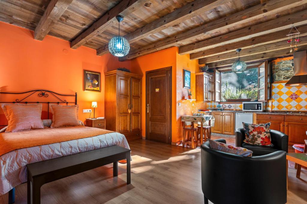 a bedroom with orange walls and a bed and chairs at Nogueira in Vega de Logares