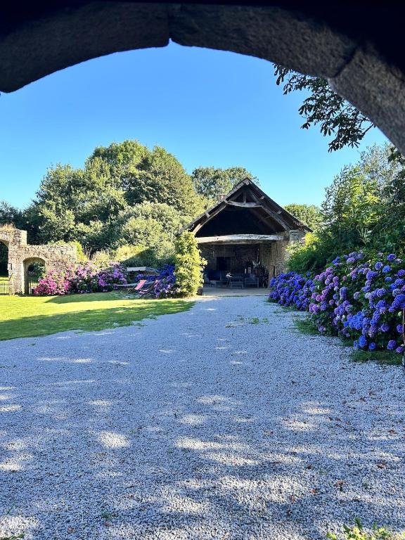 a gravel road leading to a building with purple flowers at L'annexe - gîte 6 personnes a 25 minutes de Vannes in Plumelec