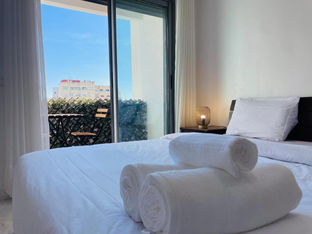 a bedroom with two white beds and a large window at Jolie appt avec Balcon - Hypercentre, proche Medina et Plage in Tangier