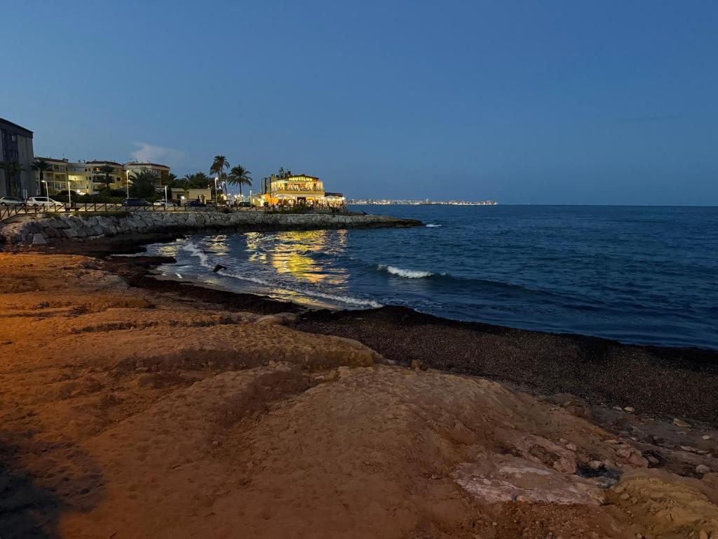 a beach with a school bus on the water at Casa Eveline in Punta Prima