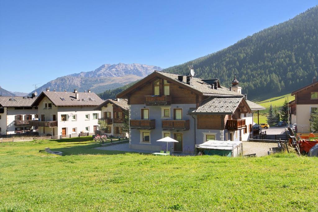 a house in a field with mountains in the background at Appartamento 8 in Livigno