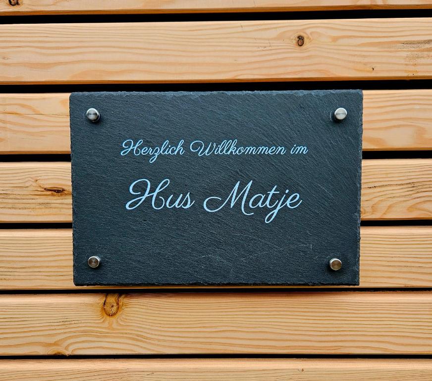 a black sign on a wooden wall with the words hush magic at Hus Matje in Langeneß