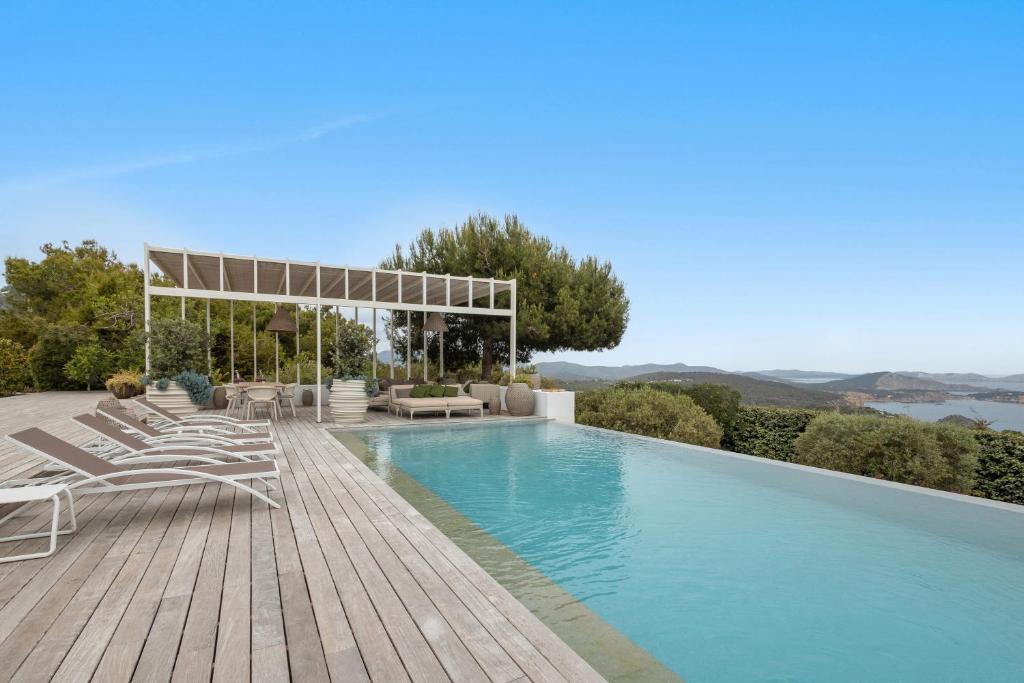 サン・ジョセップ・デ・サ・タライアにあるCasa Cayamaのラウンジチェアとスイミングプールバイザー付きのスイミングプール