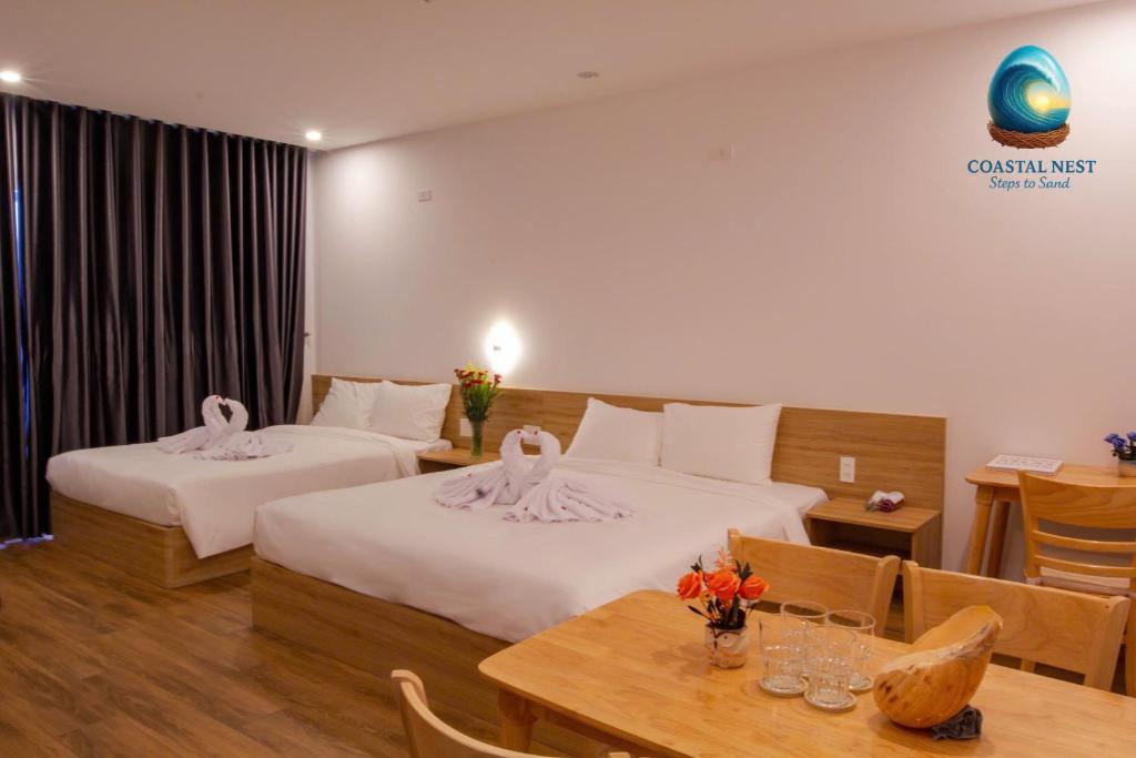 een hotelkamer met twee bedden en een tafel bij Coastal Nest - Steps to Sand in Da Nang