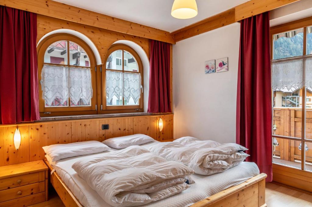a bedroom with a large bed with red curtains at Apartment Sassolungo in Campitello di Fassa