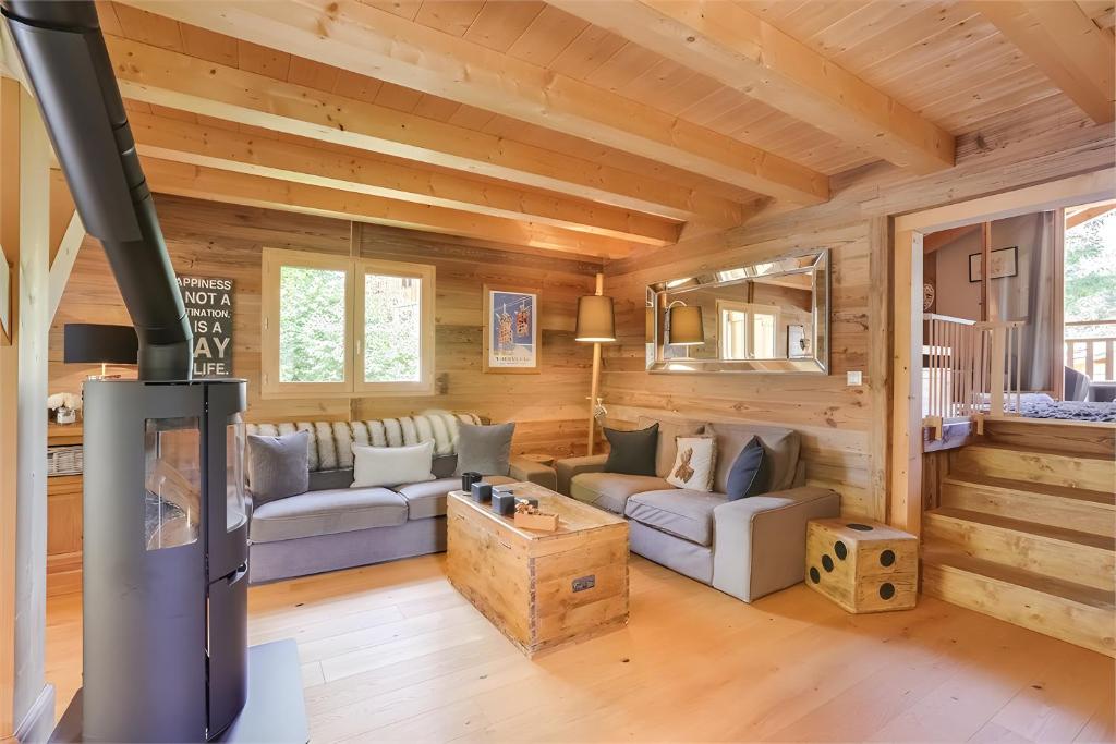 a log cabin living room with couches and a fireplace at Chalet Standing Jacuzzi in Samoëns