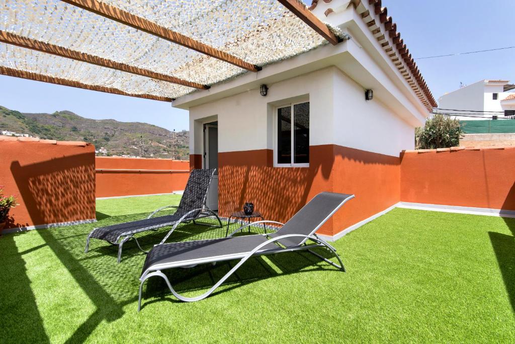 Un patio con dos sillas de jardín y una casa. en Las Monarcas, en Teror