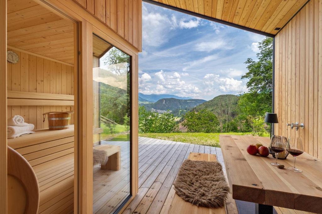 a wooden cabin with a table and a large window at Oberplunerhof Luxury Chalet Skyline in Colli in Pusteria