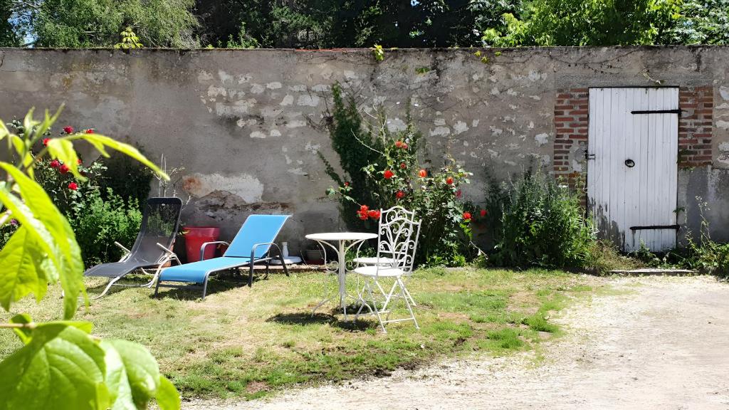 a group of chairs and a table in a yard at Chambres D'hôtes Le Petit Puits in Cheverny