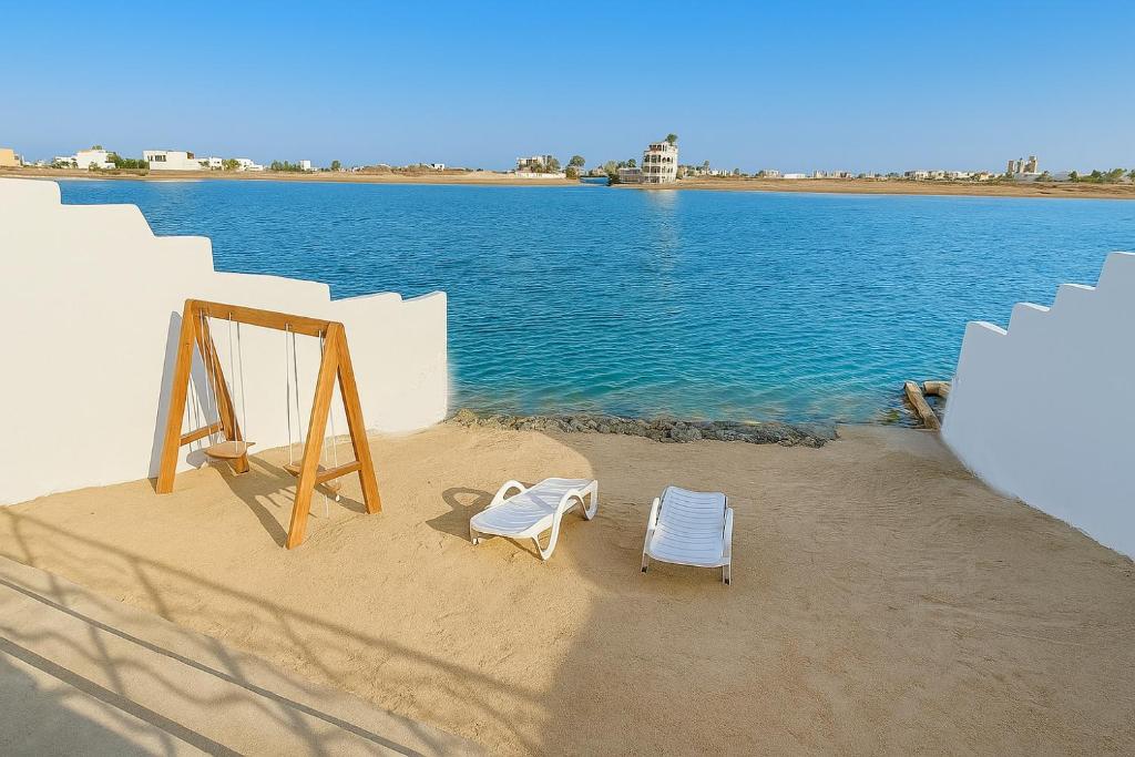 two chairs sitting on the sand next to the water at درة العروس فيلا نجمة البحر in Durat Alarous